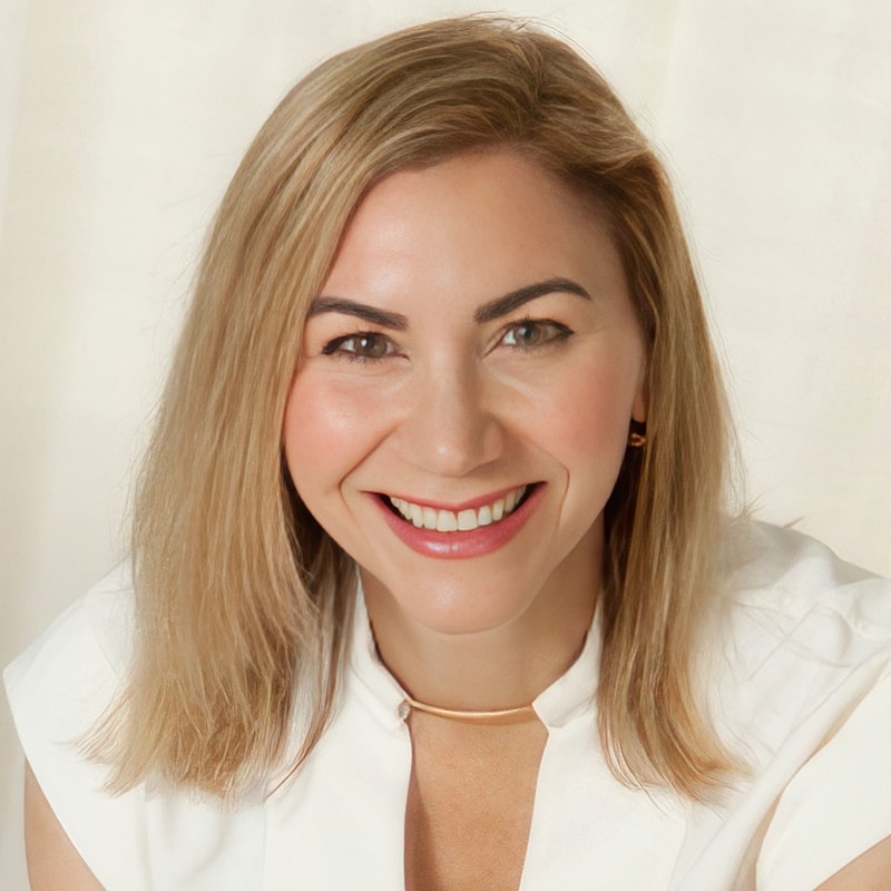 Smiling woman in white top against light background.