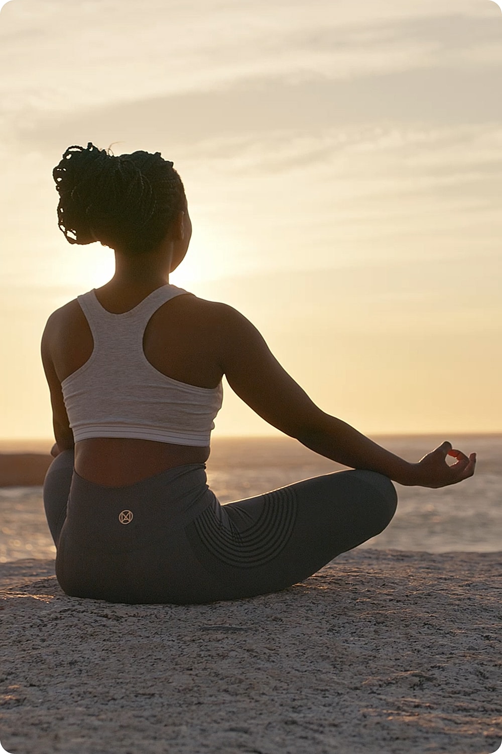Person meditating by the sea at sunset.