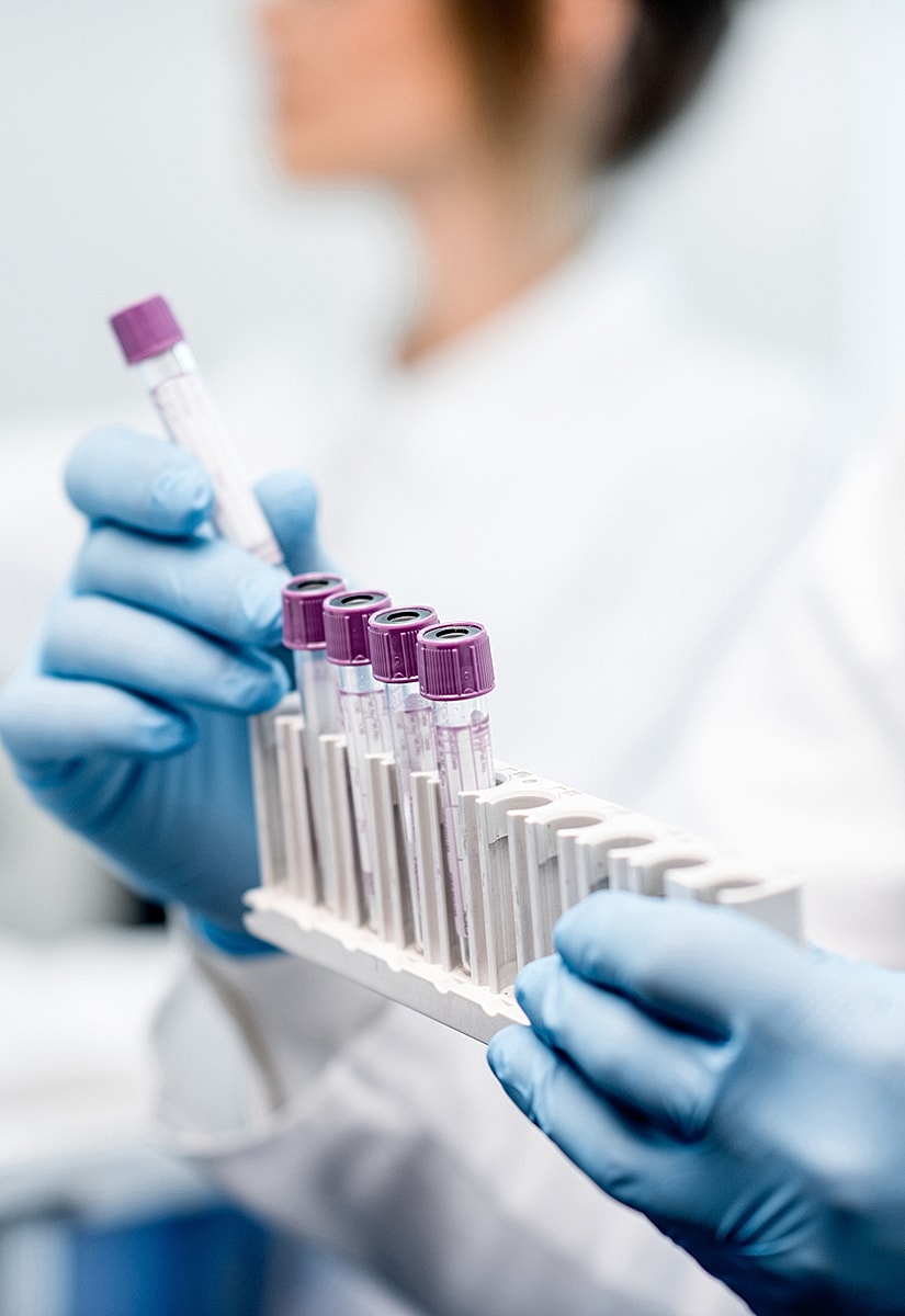 Laboratory technician holding test tubes in rack.