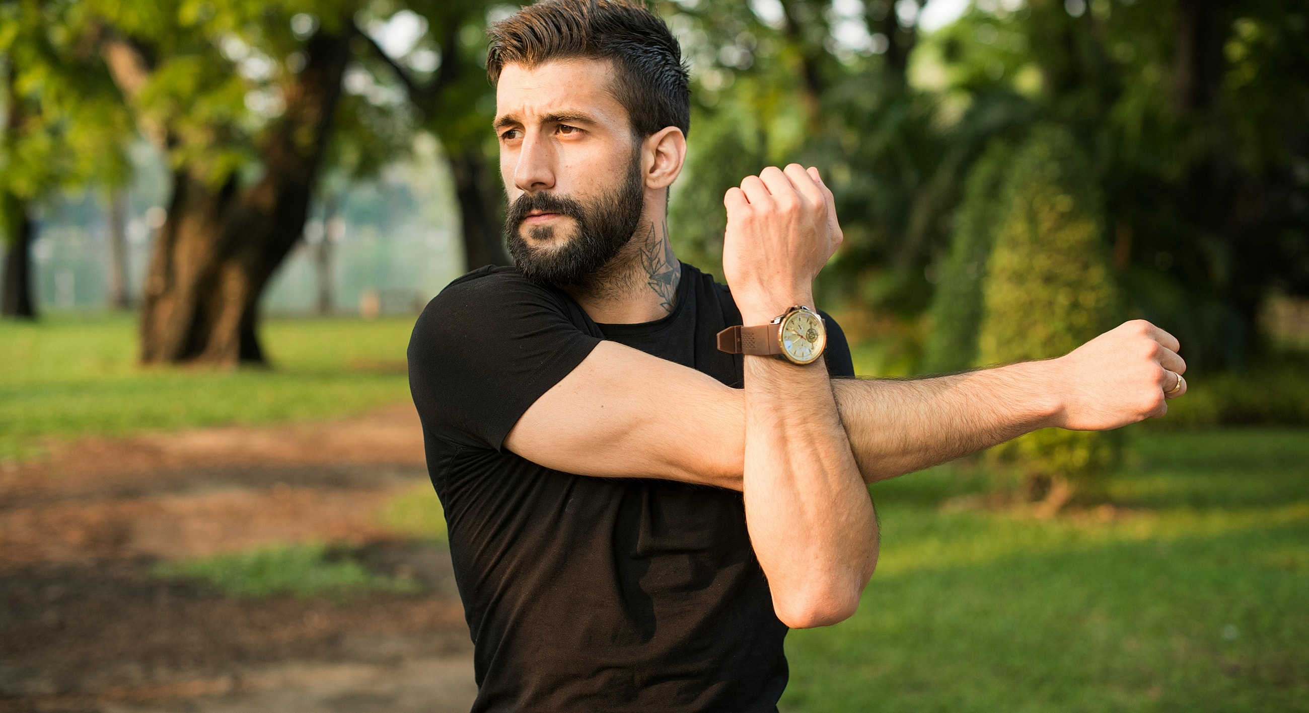 Man stretching arm in outdoor setting.
